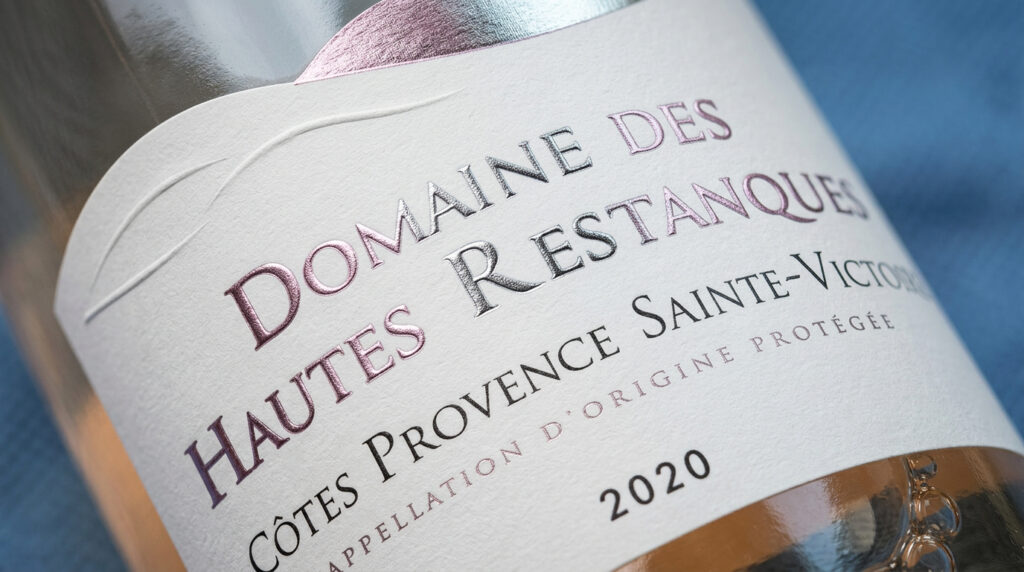 Étiquette en papier texturé épais du Domaine des Hautes Restanques, Côtes de Provence Sainte-Victoire 2020, avec gravure en relief et finition dorée. Le design minimaliste met en valeur l'appellation et l'année, soulignant l'élégance des matériaux premium pour un vin AOP.
